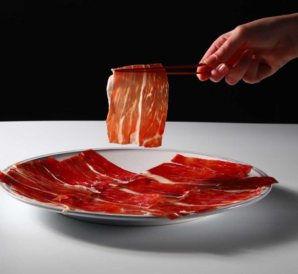 https://images.enriquetomas.com/blog/wp-content/uploads/2018/02/jamon-bellota-pata-negra-pinzas-loncheado-003-1024x942.jpg